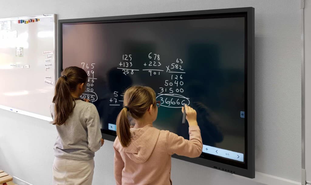 Deux élèves devant un grand tableau numérique interactif